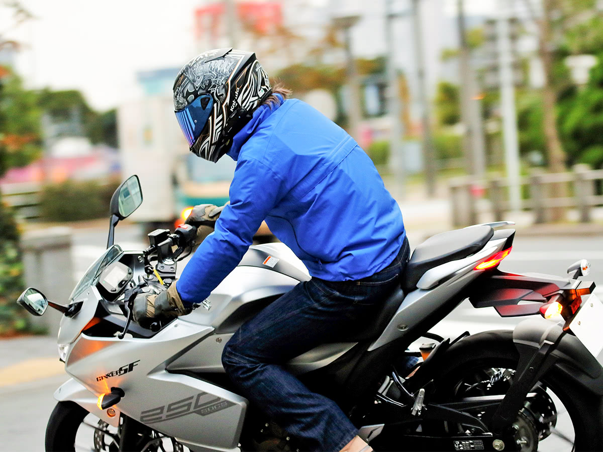 GOLDWIN GSM22900 MOTORCYCLE GWM ゴアテックスマルチフーデッドジャケットを着てバイクで走るライダー